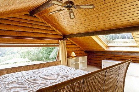 Een slaapkamer in een blokhut met een bed en een plafondventilator.