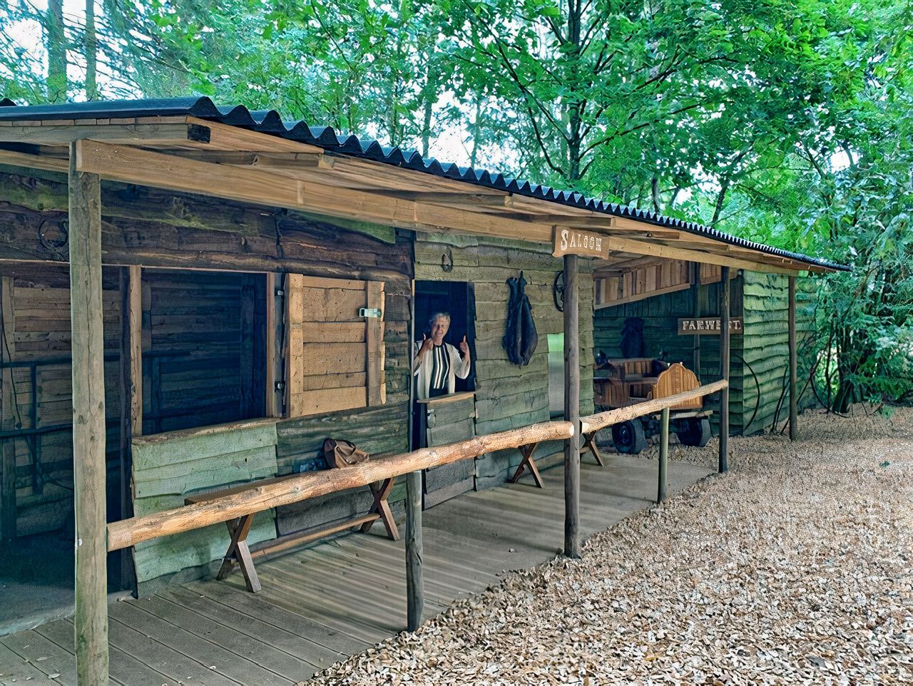Un homme se tient devant une cabane en bois dans les bois.