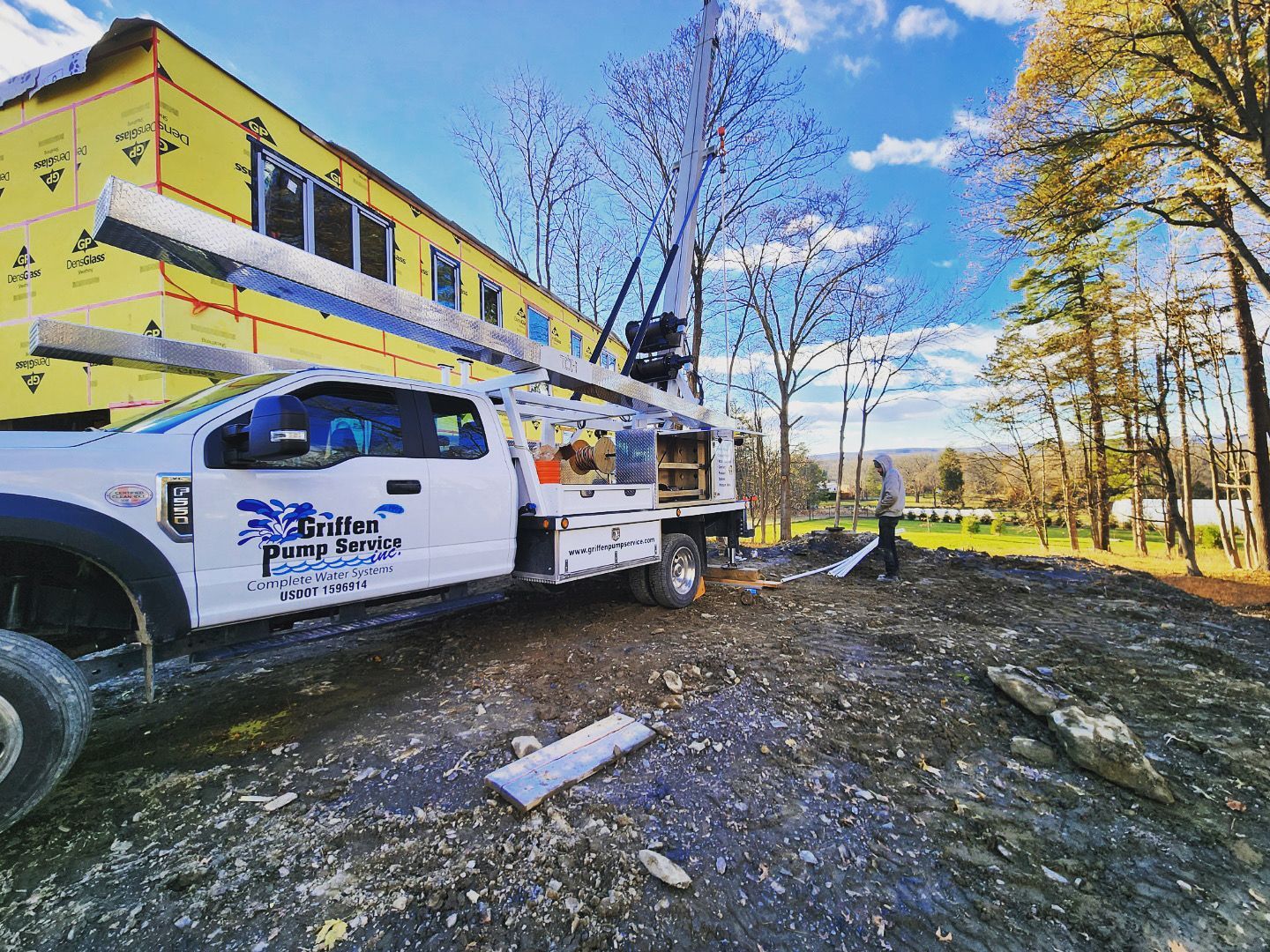 A white truck is parked in front of a building under construction.
