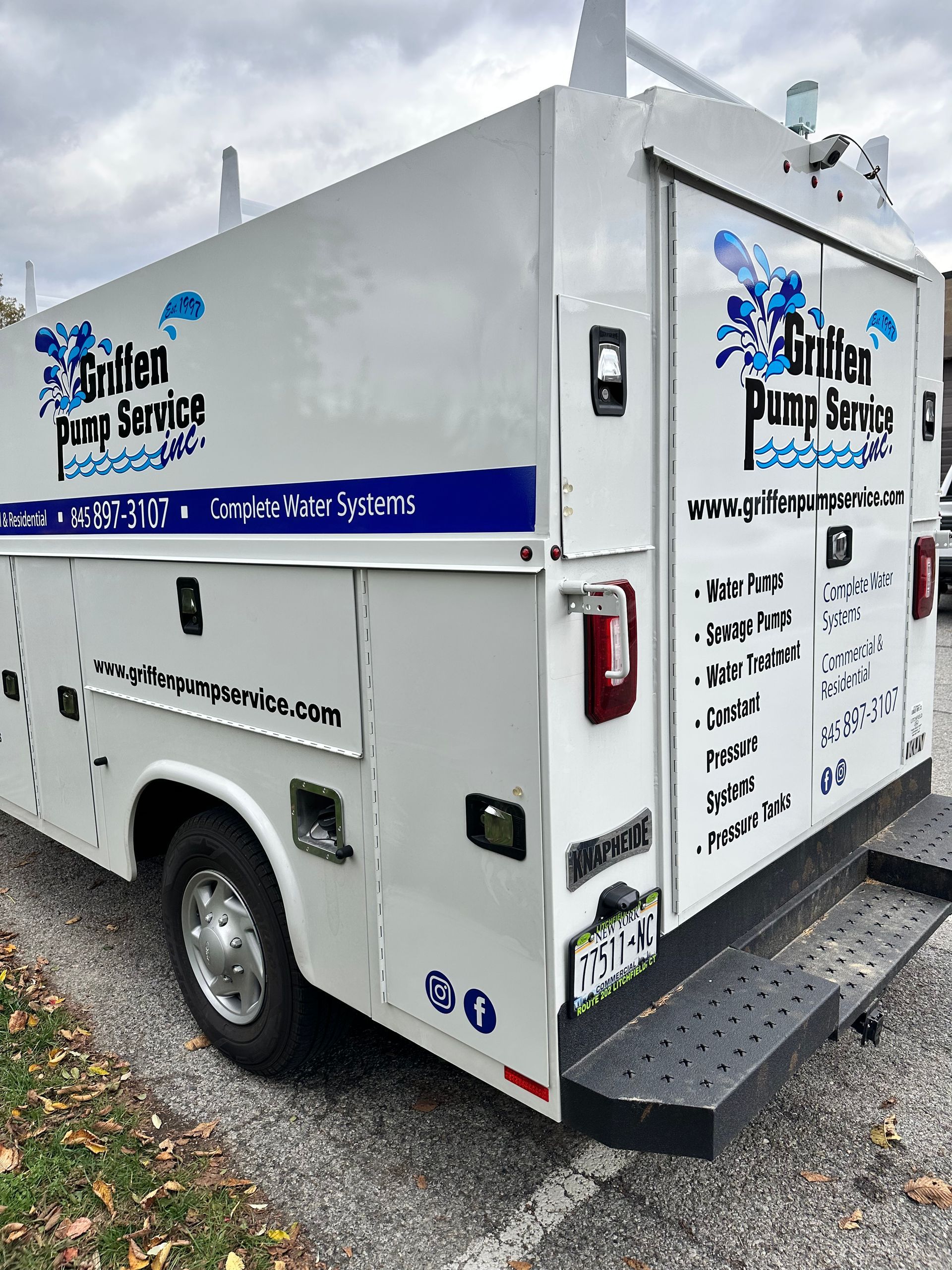 A white utility truck is parked on the side of the road.