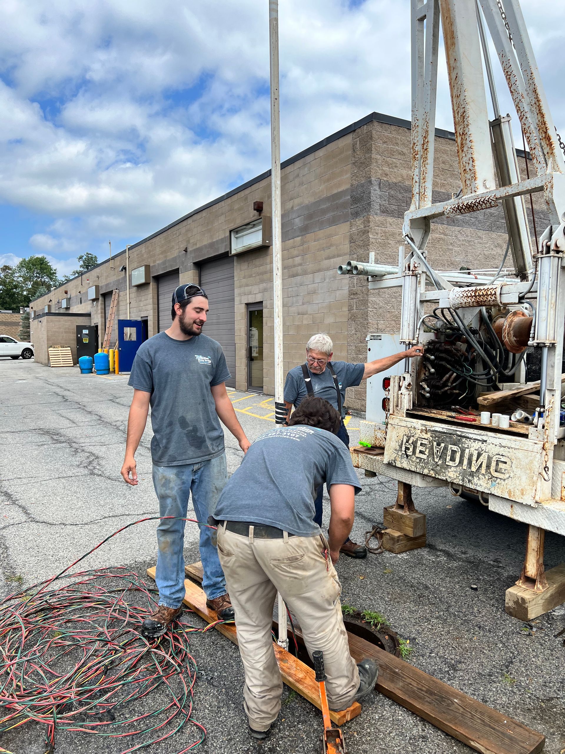 A group of men are working on a drilling rig in front of a building.