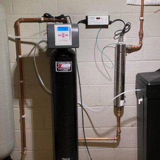 A water filter is attached to a wall with copper pipes