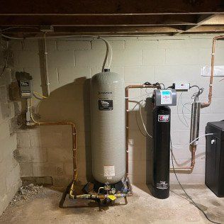 A water heater is sitting in a basement next to a water filter.