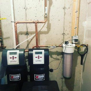 Two water filtration systems are connected to a wall.