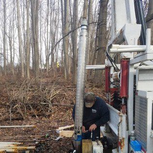 A man is working on a water pump in the woods