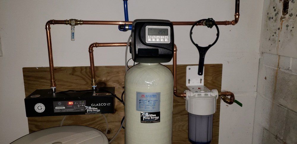 A water filter is hanging on a wall next to a toilet.