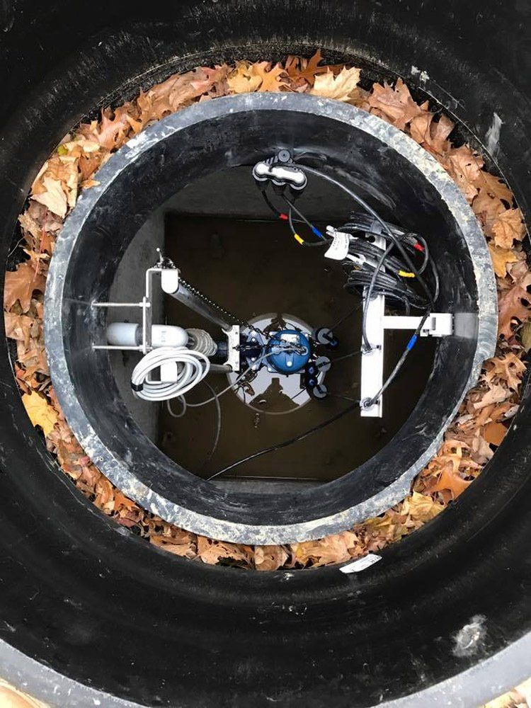 The inside of a manhole cover with leaves around it.