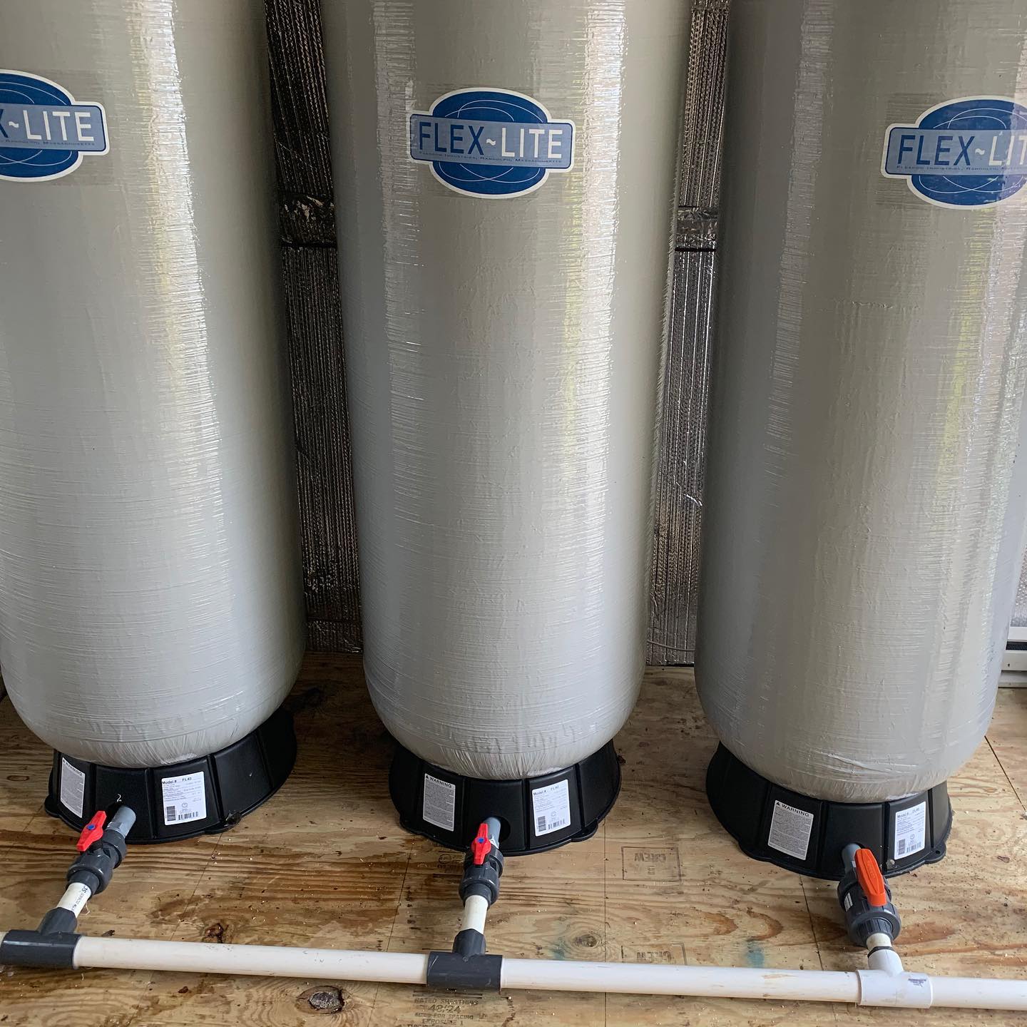 Three flex-lite tanks are sitting on a wooden table.