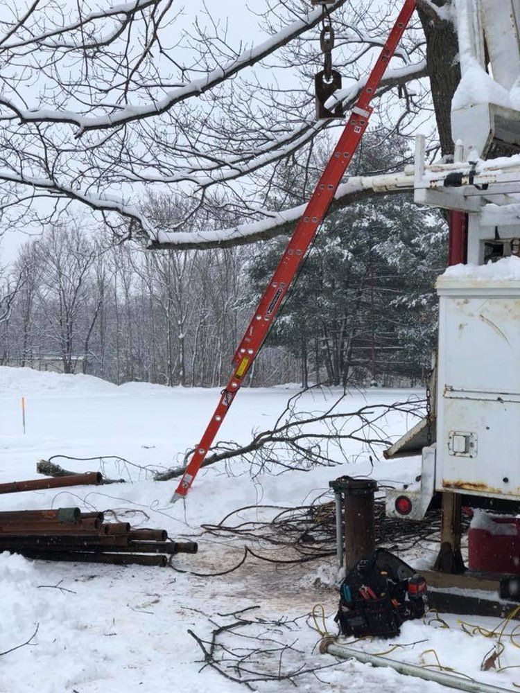 A red ladder is hanging from a crane in the snow.