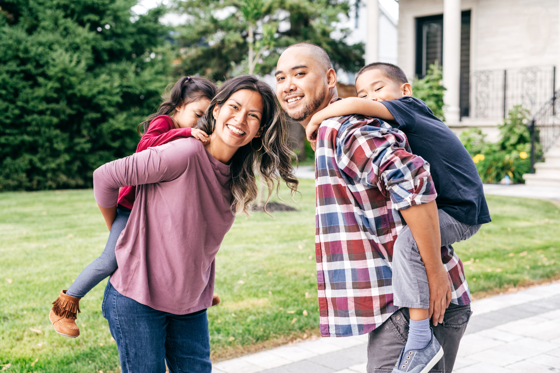 A family is posing for a picture in front of their house.