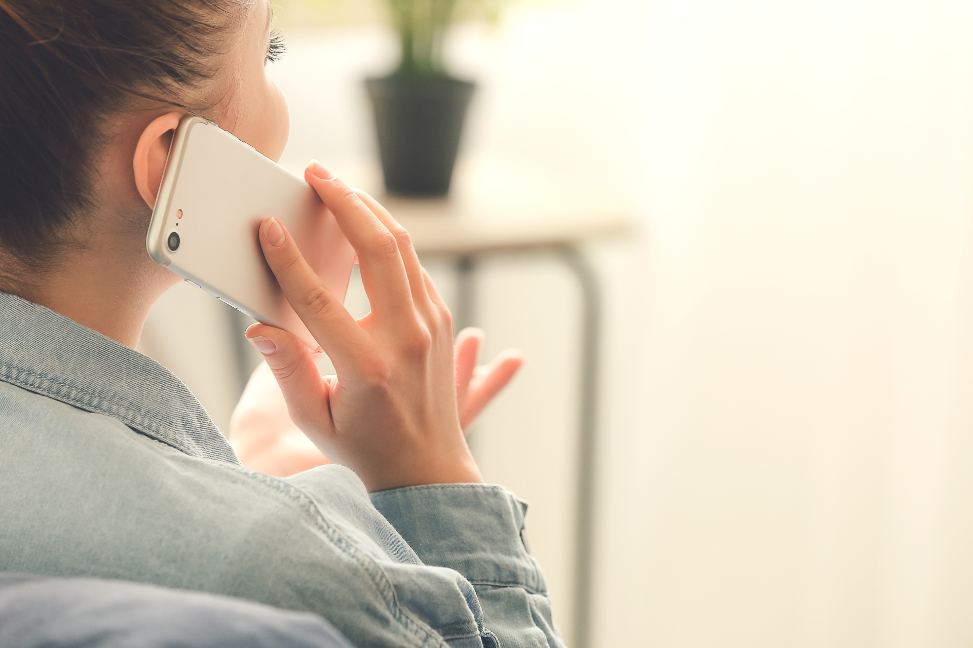 A woman is sitting on a couch talking on a cell phone.