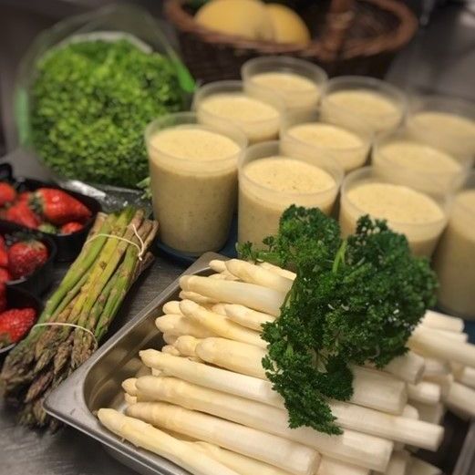 Een schaal met asperges naast een schaal met aardbeien