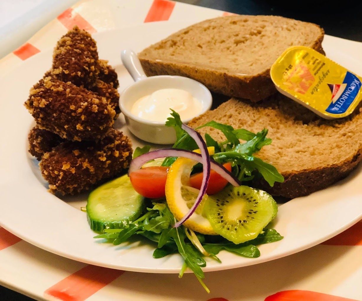 Een bord met eten en een bakje mosterd erop