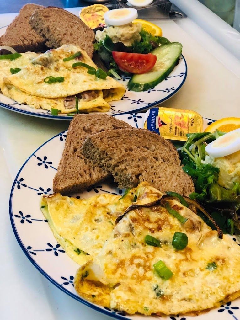 Twee borden met eten, eieren, brood en groenten op tafel.