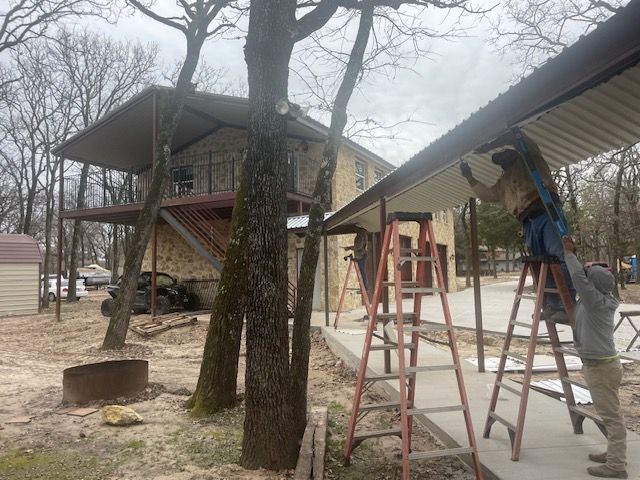 A man on a ladder is working on the roof of a house.