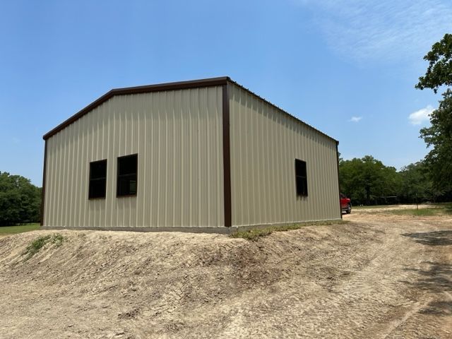 A metal building with two windows sits on top of a dirt hill