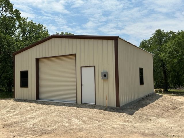 A metal building with a garage door and a white door