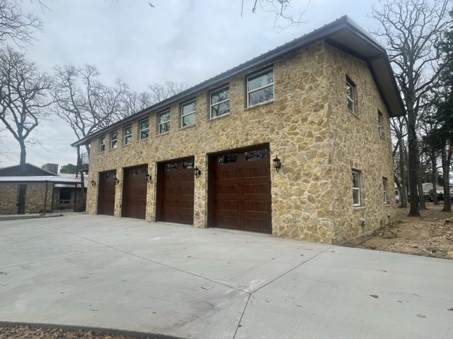 A large stone building with three garage doors and a driveway.