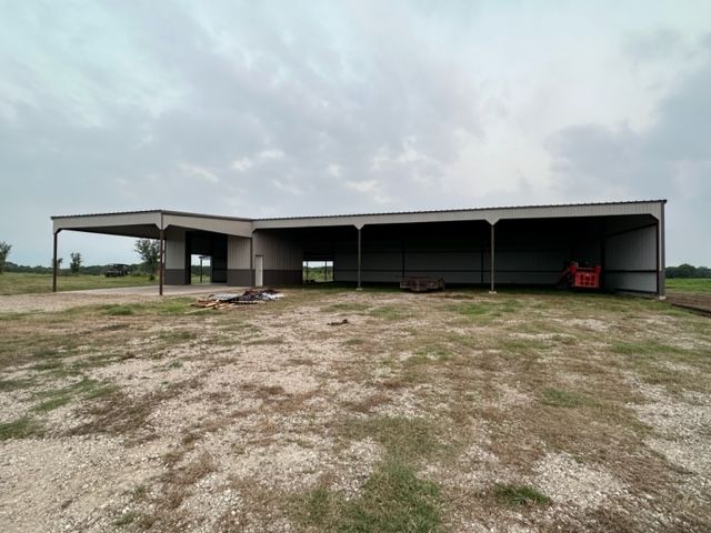 A large building is sitting in the middle of a dirt field.