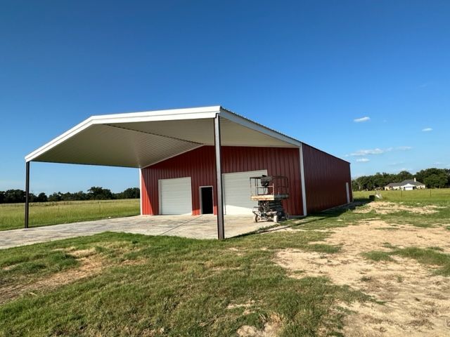A red barn with a white roof is sitting in the middle of a grassy field.