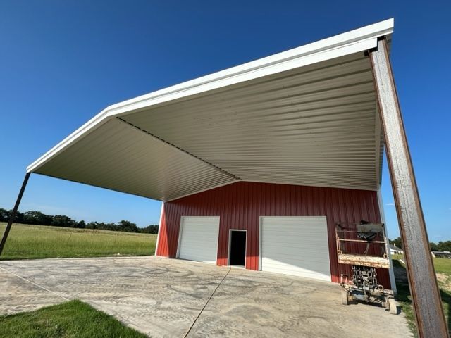 Red building with white garage doors and a white overhang, under a blue sky.