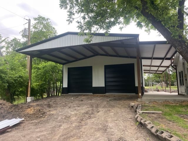A white and black garage with a carport underneath it.
