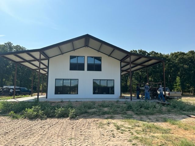 A white building with a metal roof and a lot of windows