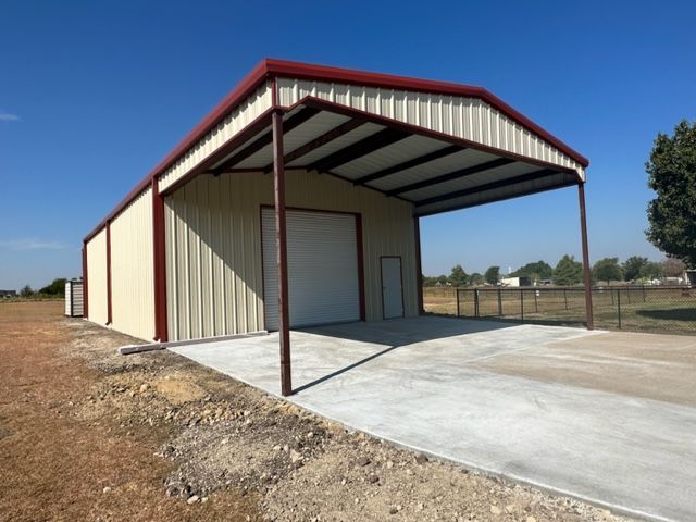 A metal building with a concrete driveway underneath it