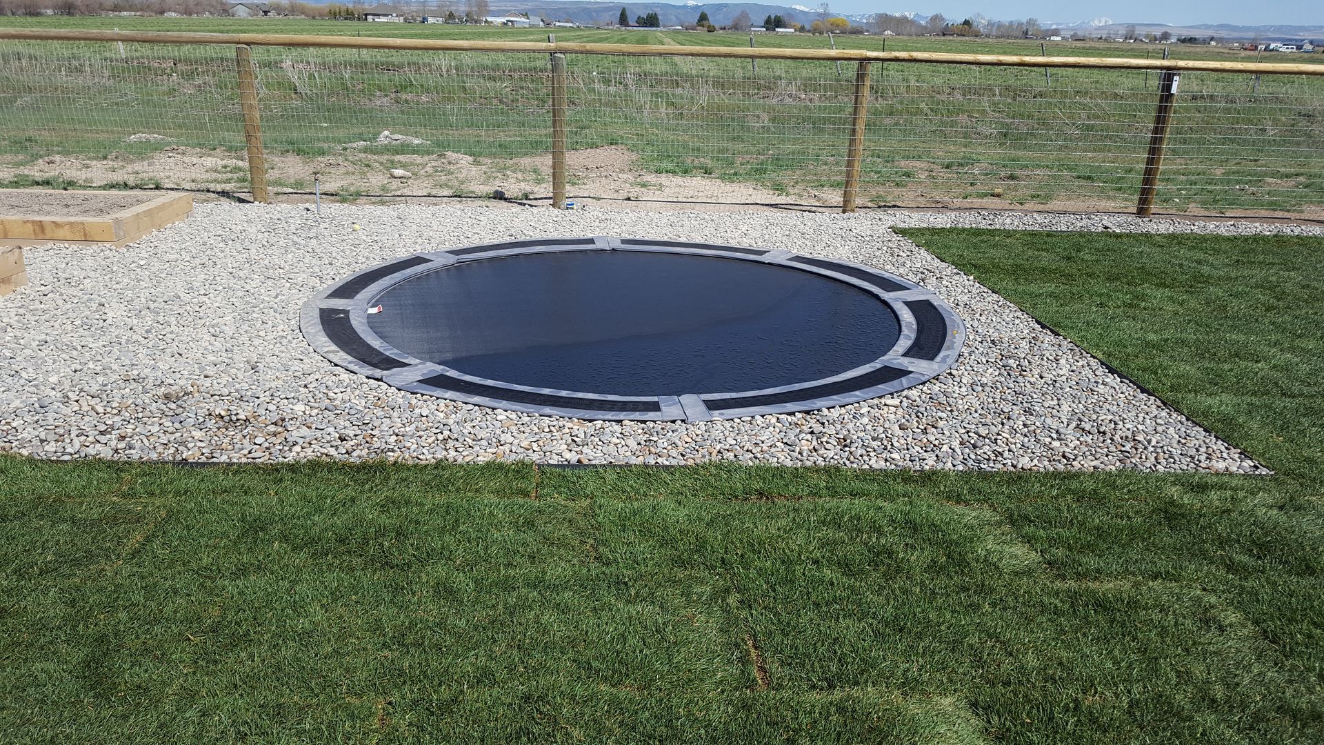 A trampoline is sitting on top of a lush green field.