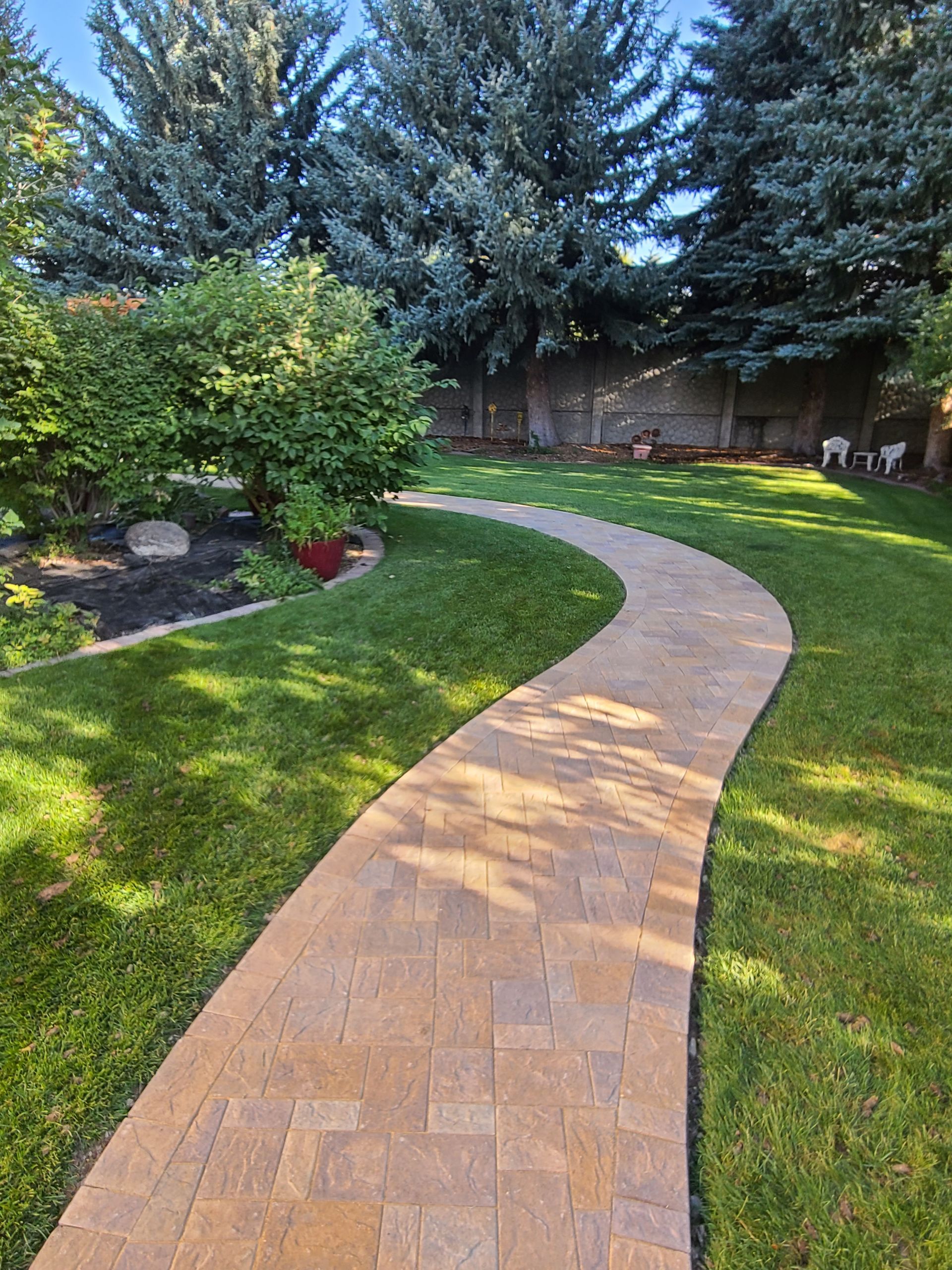 A brick walkway going through a lush green yard.