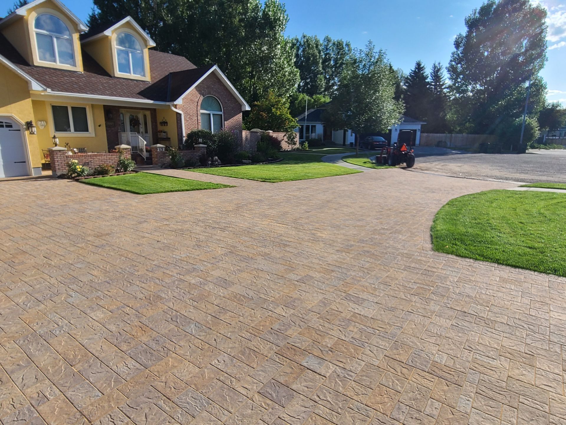 A yellow house with a brick driveway in front of it