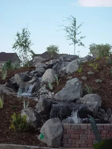 A small waterfall is surrounded by rocks and trees