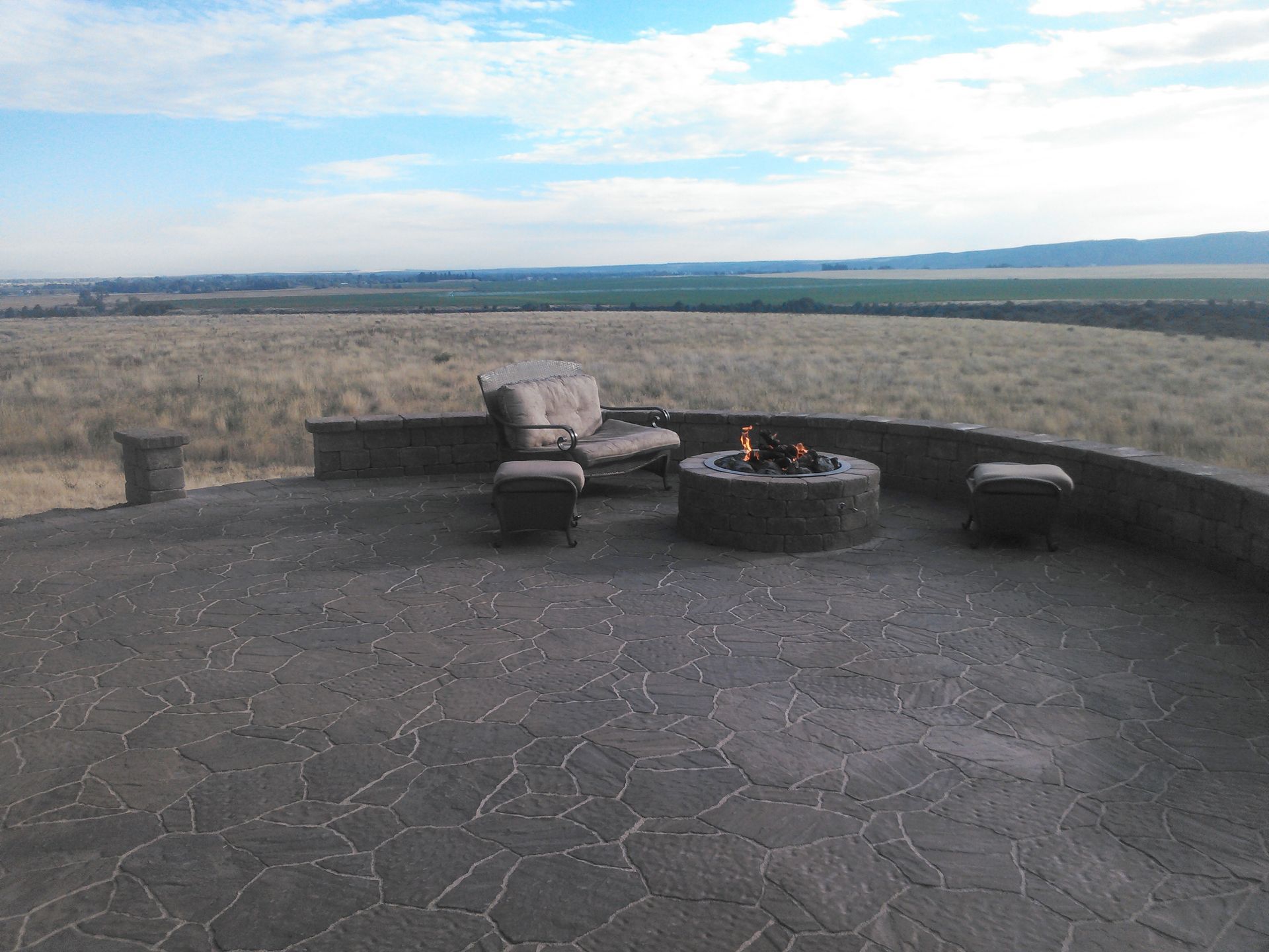 A patio with a fire pit and a view of a field