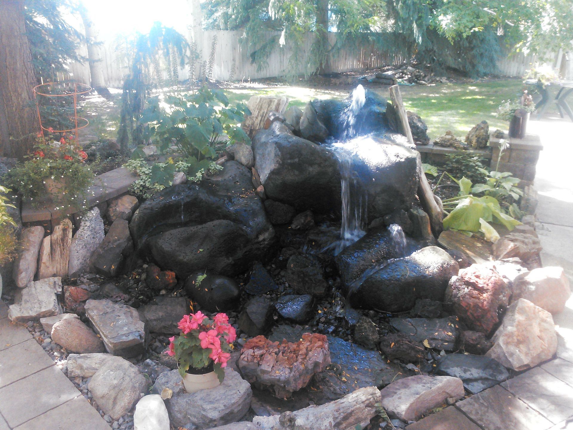 A waterfall is surrounded by rocks and flowers in a garden.
