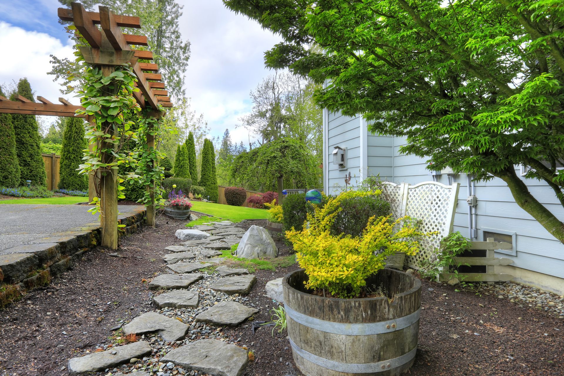 A wooden barrel filled with plants is in the middle of a garden.