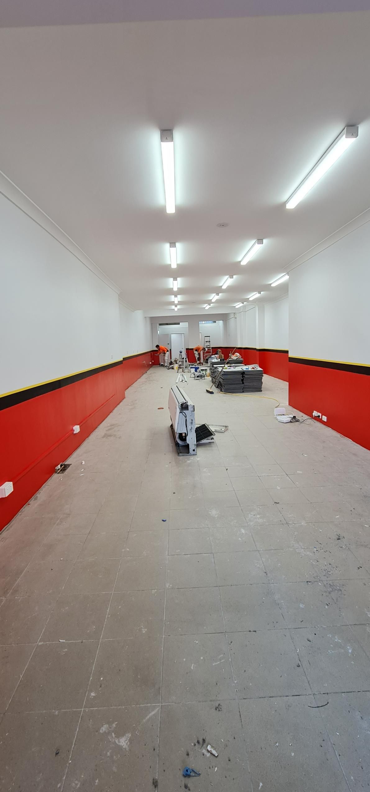 A Long Empty Room With Red Walls And A Carpeted Floor — Blue Painting & Decorating In Taylor, ACT