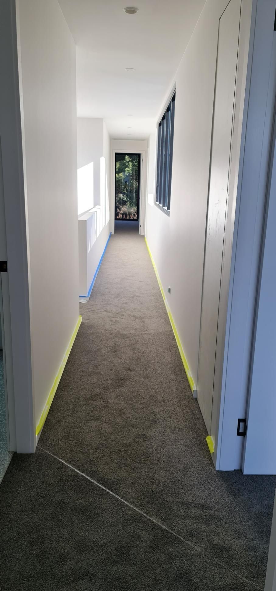 A Long Hallway With A Carpeted Floor And White Walls — Blue Painting & Decorating In Taylor, ACT