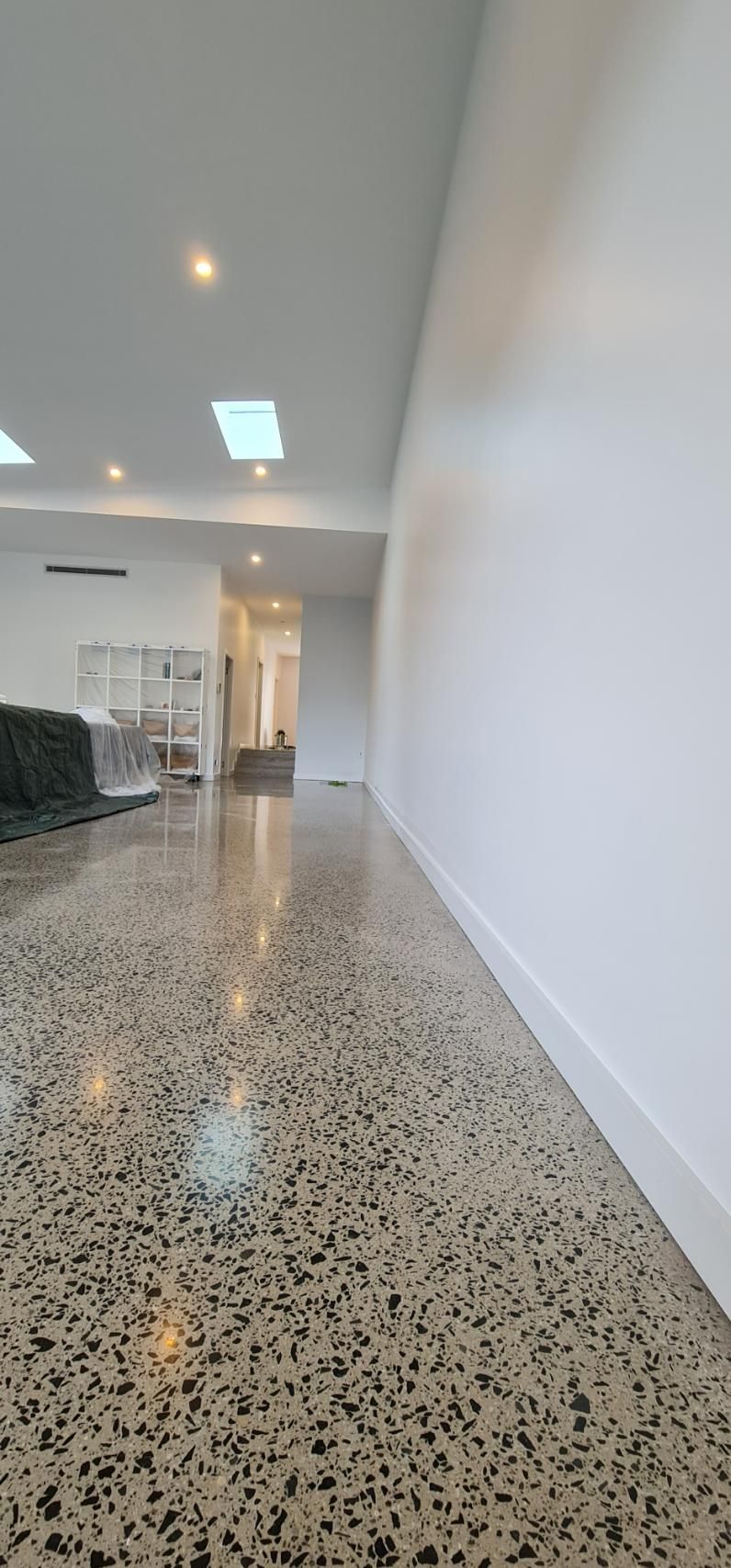 A Long Hallway With A Concrete Floor And White Walls — Blue Painting & Decorating In Taylor, ACT