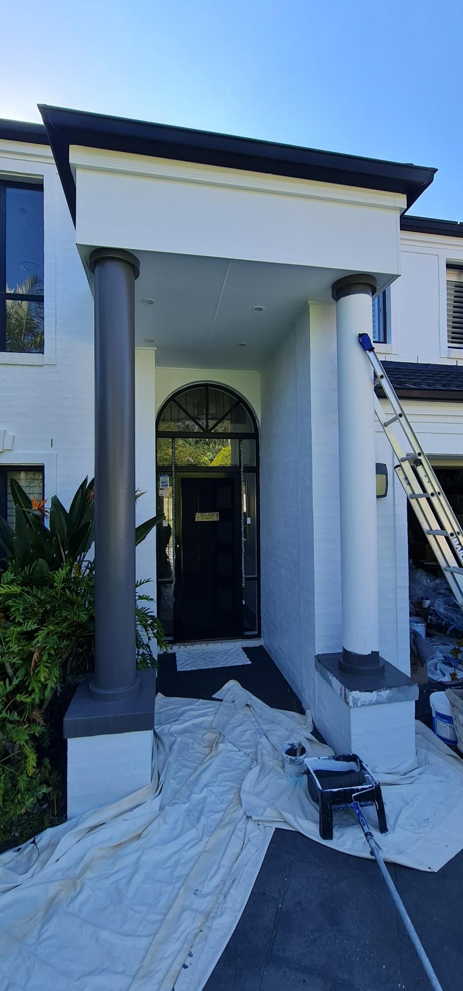 A White House With A Black Door Is Being Painted — Blue Painting & Decorating In Taylor, ACT