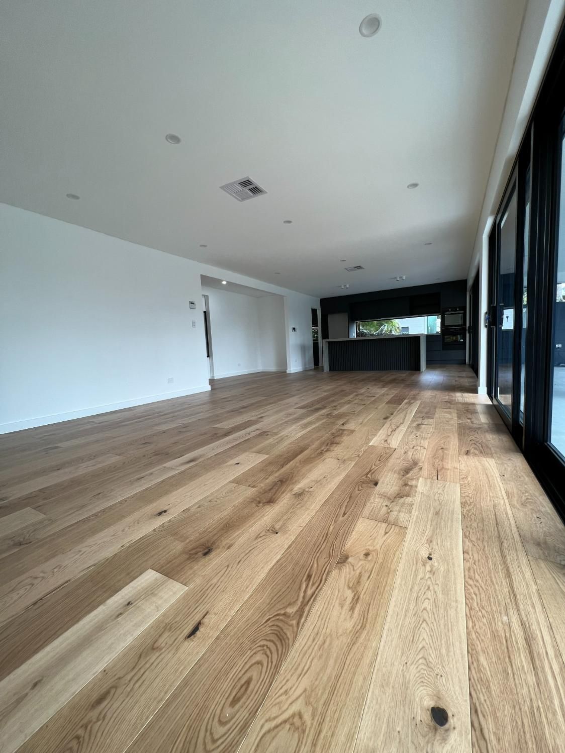 A Large Empty Room With Hardwood Floors And White Walls — Blue Painting & Decorating In Taylor, ACT