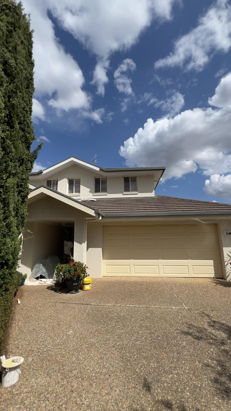 A Large White House With A Garage Door And A Tree In Front Of It — Blue Painting & Decorating In Taylor, ACT