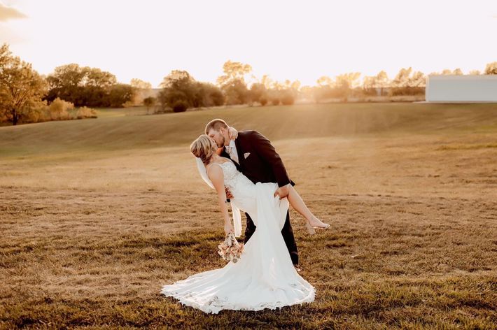 bride and groom dip kiss in front of gorgeous outdoor setting in field