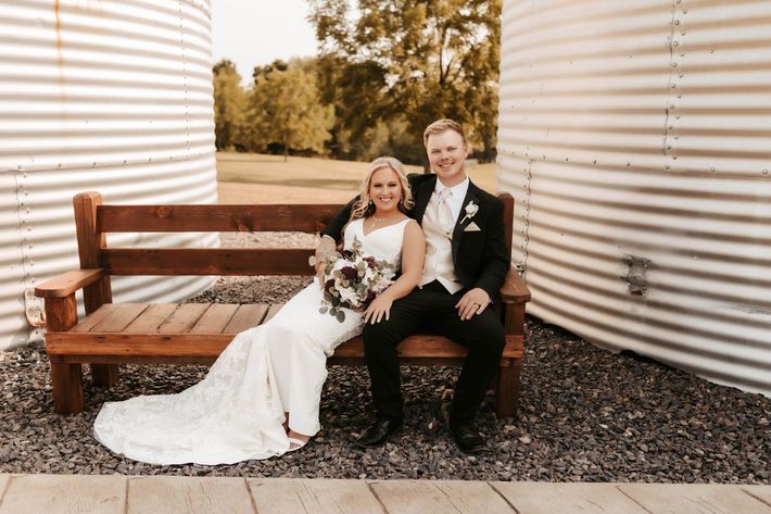 bride and goom posing on rustic bench 