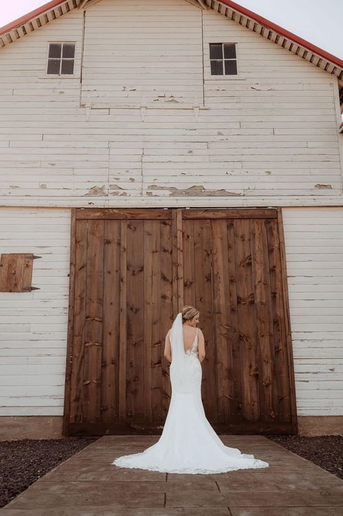 bride posing with dress in front of barn doors