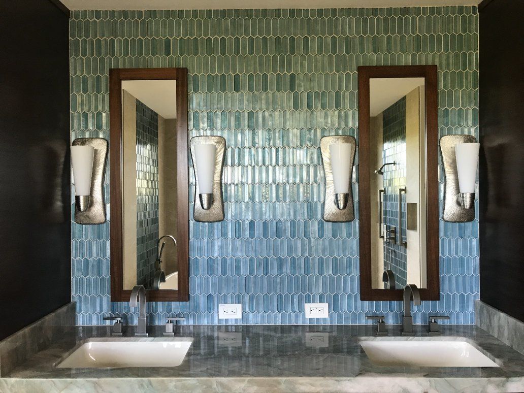 a bathroom with two sinks and two mirrors on tiled wall .