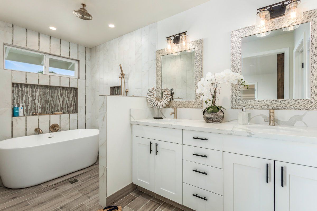 a bathroom with a tiled bathtub , sink and mirror.