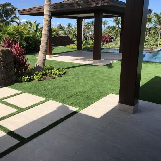 a lawn with a pergola and a pool in the background