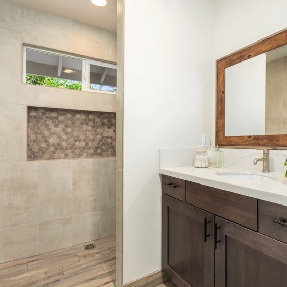 a bathroom with a sink , mirror and walk in tile shower .