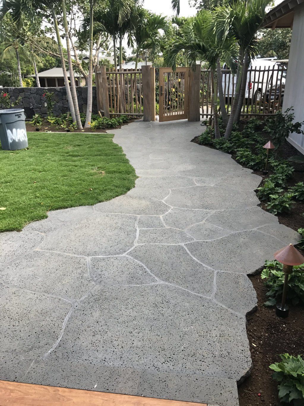a stone  walkway leading to a gate in a backyard.