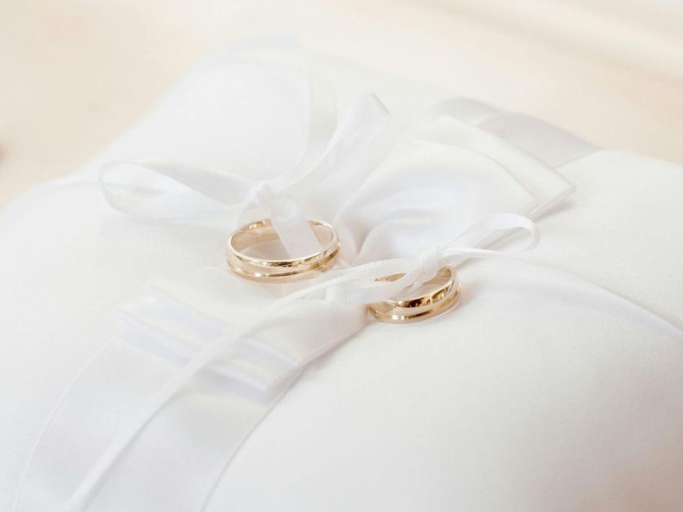 A pair of wedding rings sitting on top of a white pillow.